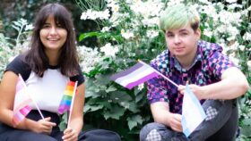 Three of Just Like Us' young volunteers waving LGBT+ Pride flags