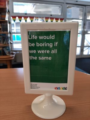 A photo from School Diversity Week celebrations of a Just Like Us poster in a school library that says 'Life would be boring if we were all the same'