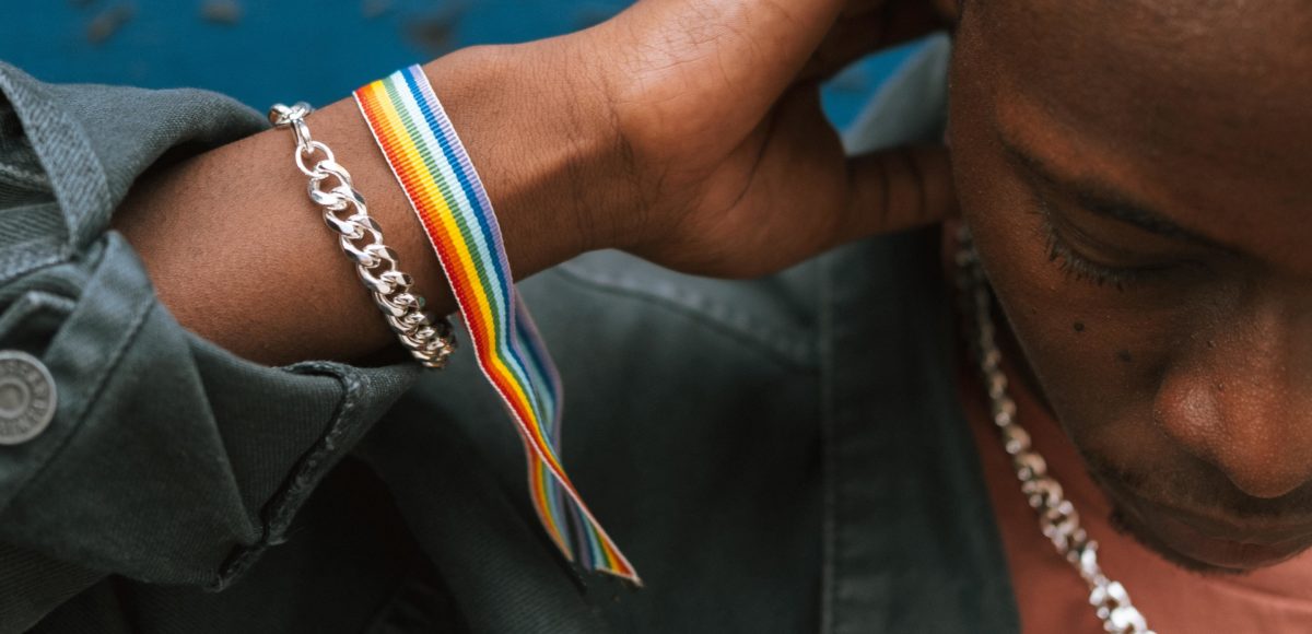 A young Black man wearing a rainbow ribbon