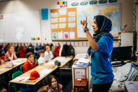 A teacher wearing a hijab stands in front of a class of children during School Diversity Week