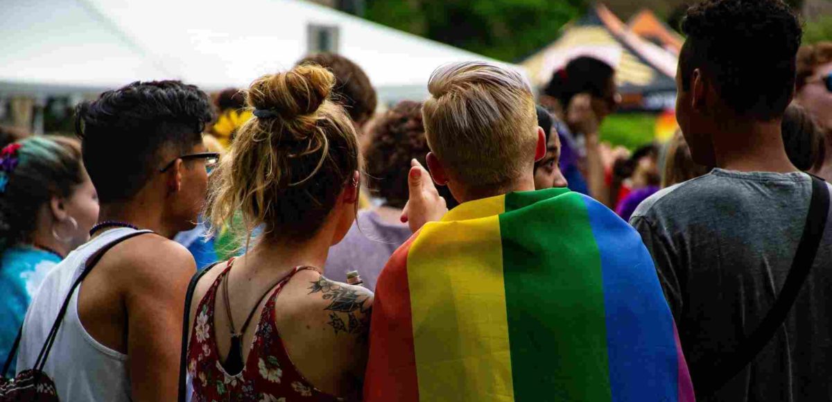 A photo of young people, one is wearing a Pride flag