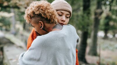 Two young adults hug in the street