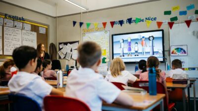 School pupils watch a video in a classroom decorated with rainbow bunting for School Diversity Week